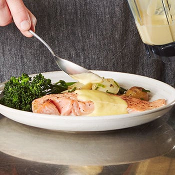 Person adding sauce to plated dish