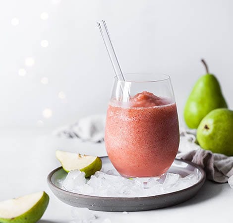 Holiday Fruit Smoothie holiday fruit smoothie with a straw in it and pears in the background