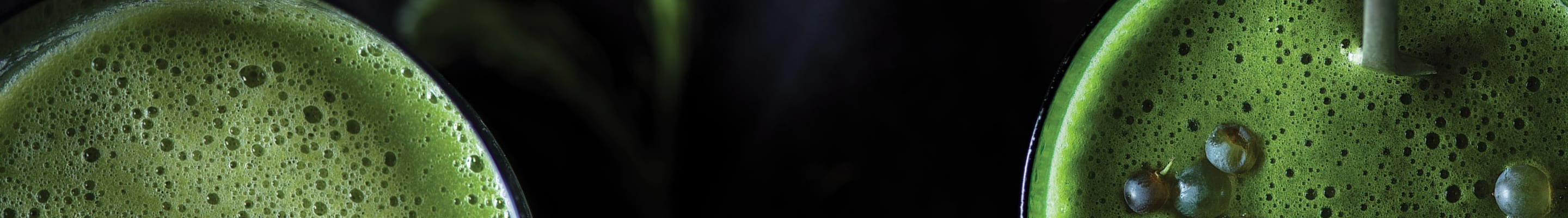Two green smoothies on a black background
