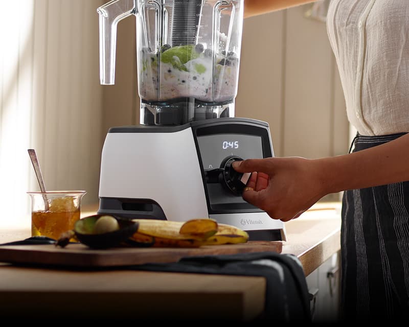 White vitamix machine with user blending ingredients